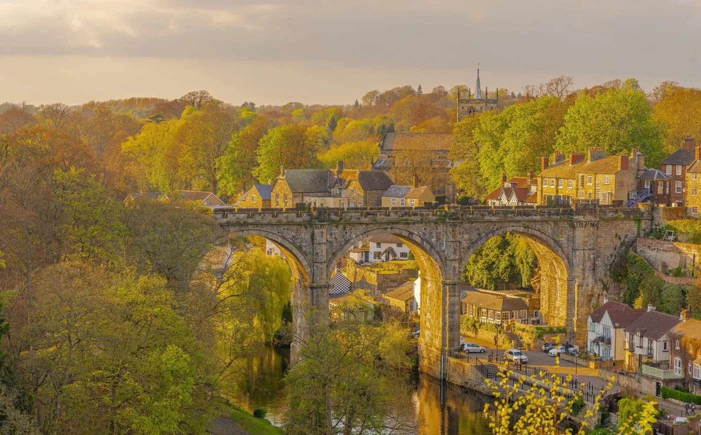 Stone railway viaduct over the river in a Yorkshire town at golden hour